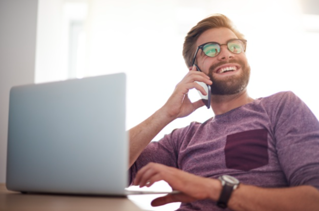 Man working phone home – iPECS phone sysem Man on phone working from home at laptop using iPECS phone system